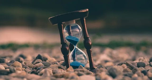 Tilted hourglass on pebbles representing the moment every startup needs security leadership, from IOmergent fractional CISO services.