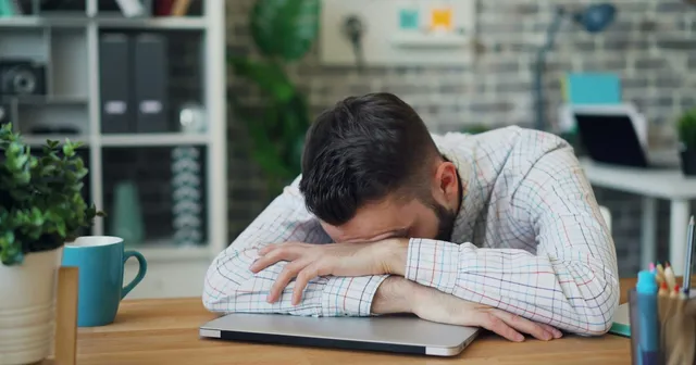 Exhausted security professional with head down on laptop, overwhelmed by cloud security alerts that IOmergent managed CSPM helps prioritize.